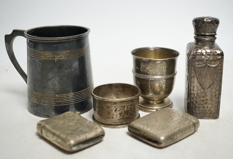 A group of small silver to include a christening mug, 143g, an egg cup, ten various napkin rings, 184g, a spot hammered bottle, a sherry label, six vesta cases, 152g and a caddy spoon. Condition - fair